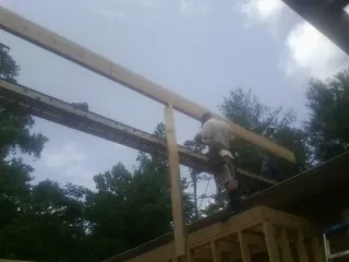 Carpenter setting a ridge beam over a new addition frame — Ice Dam Removal by Roofing Brothers in Meacham