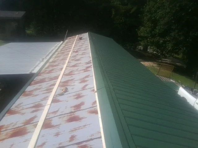 Old rusted panels beside newly installed green metal roofing — Wind Damage Roof Repair by Roofing Brothers in Meacham
