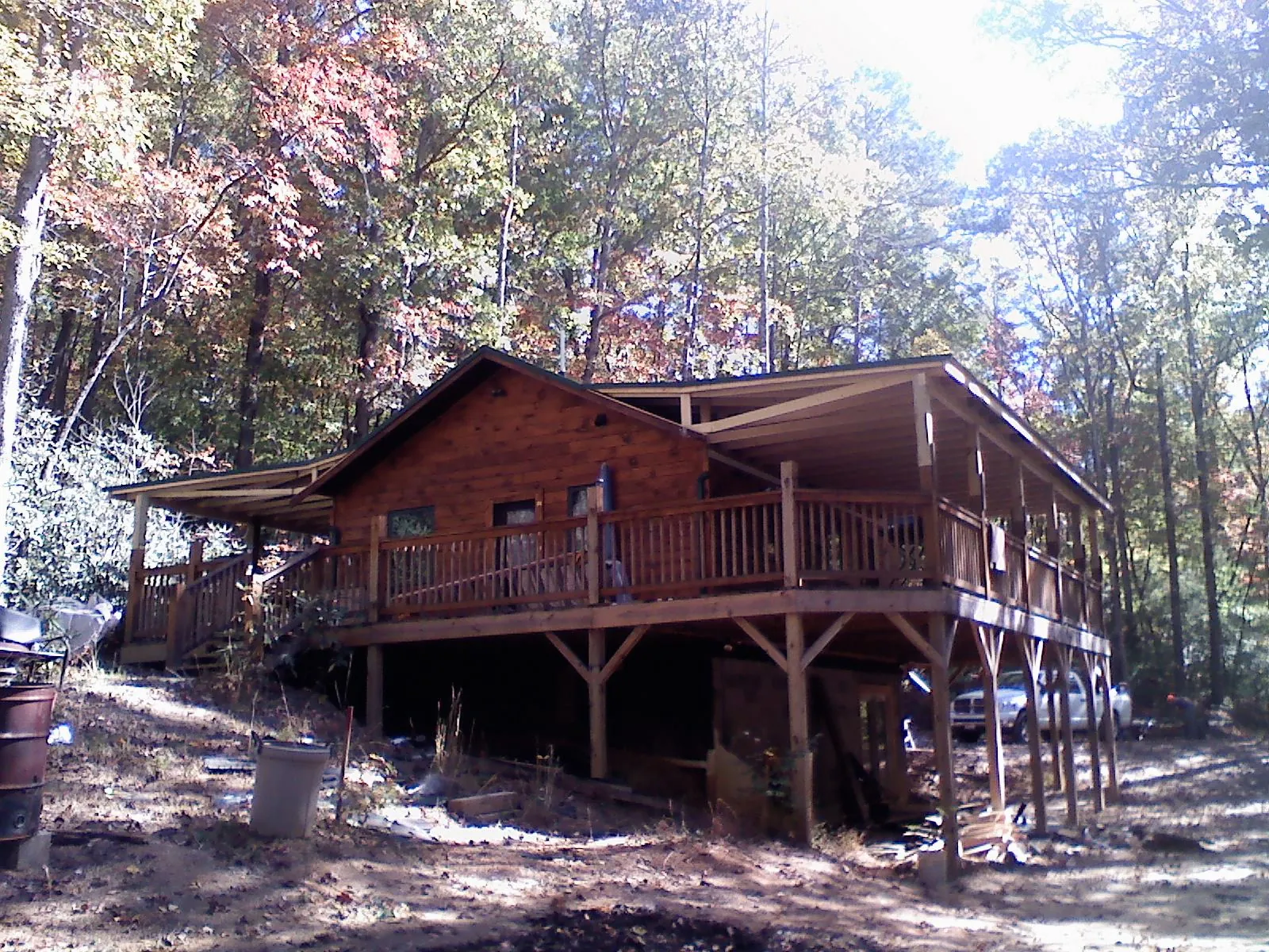 Log cabin with a wraparound porch and metal roof in the fall in Meacham