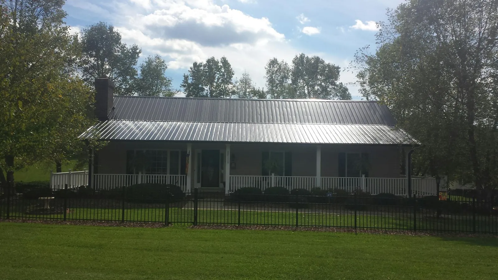 Gray metal roof on a brick ranch with a full width front porch — Gutter Guard Installation work by our crew in Meacham