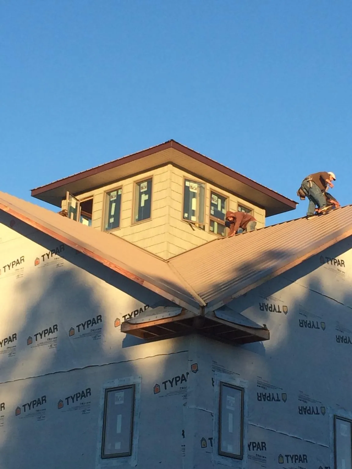 Roofers working around a rooftop cupola on a new metal roof at sunset — Roof Waterproofing in Meacham by Roofing Brothers